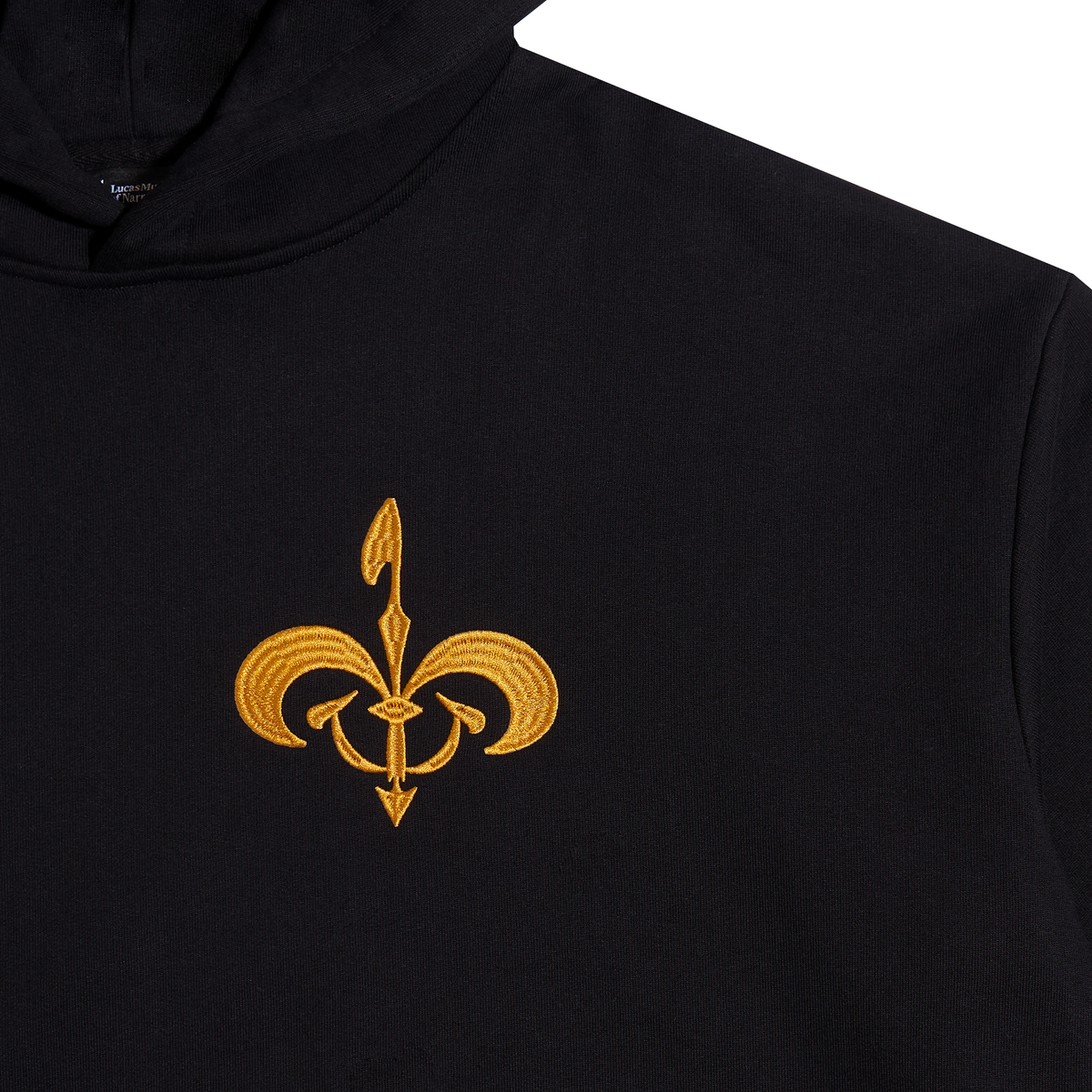 Close-up of a black hoodie featuring an embroidered gold fleur-de-lis symbol on the chest, set against a plain white background.