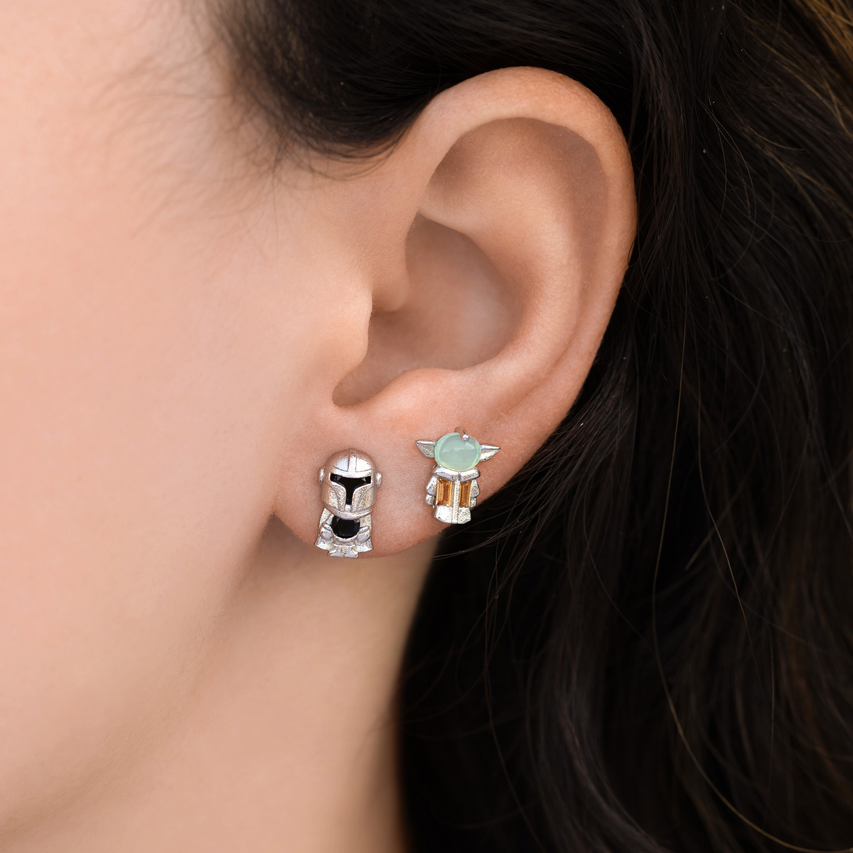 Galactic Crew Silver Stud Set featuring Grogu and a Mandalorian helmet studs with crystal accents, photographed on a model's ear.