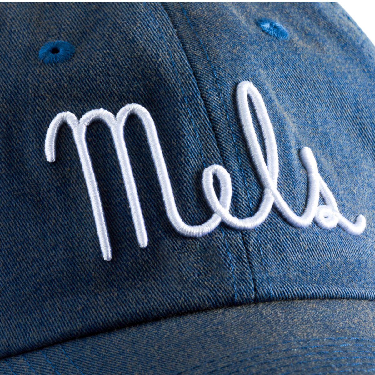Close-up of a cotton washed denim dad hat featuring white embroidered Mel's Diner emblem.