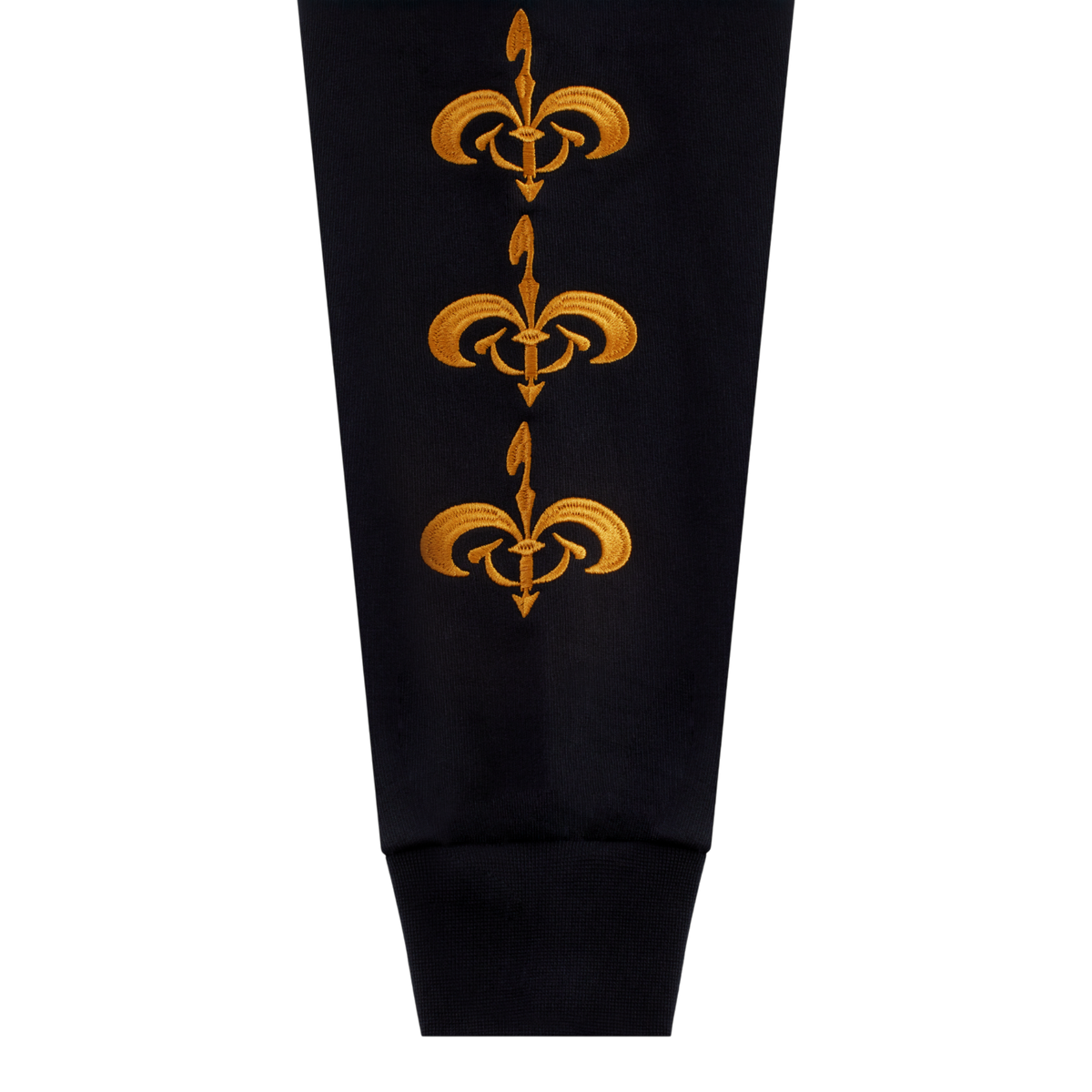 Close-up of a black sleeve with three vertical gold fleur-de-lis motifs on the upper section and a ribbed cuff at the bottom.