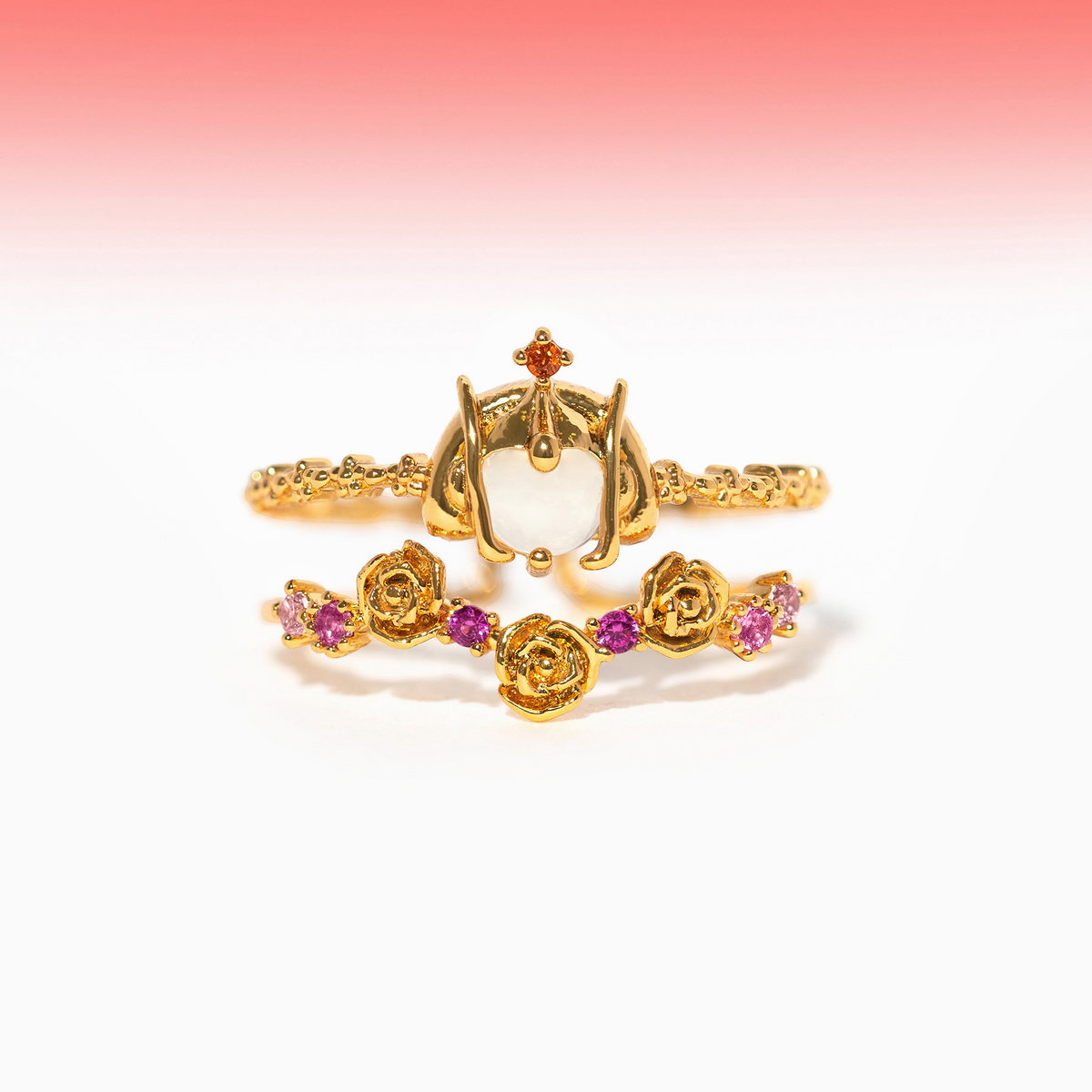 Two-piece gold-tone Padmé Amidala ring set featuring an ornate crown motif with a white stone and a matching rose-pattern band with pink gemstone accents, shown on a plain background.