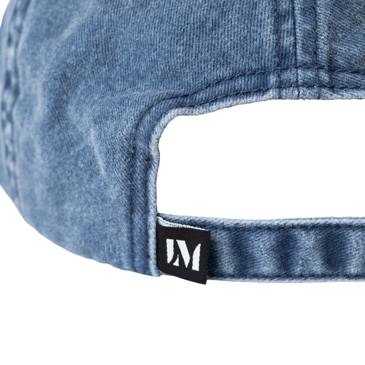 Washed cotton cap featuring embroidered text reading “Unreliable Narrator,” with an adjustable back strap and metal fastener. Interior seams are finished with logo-branded binding.