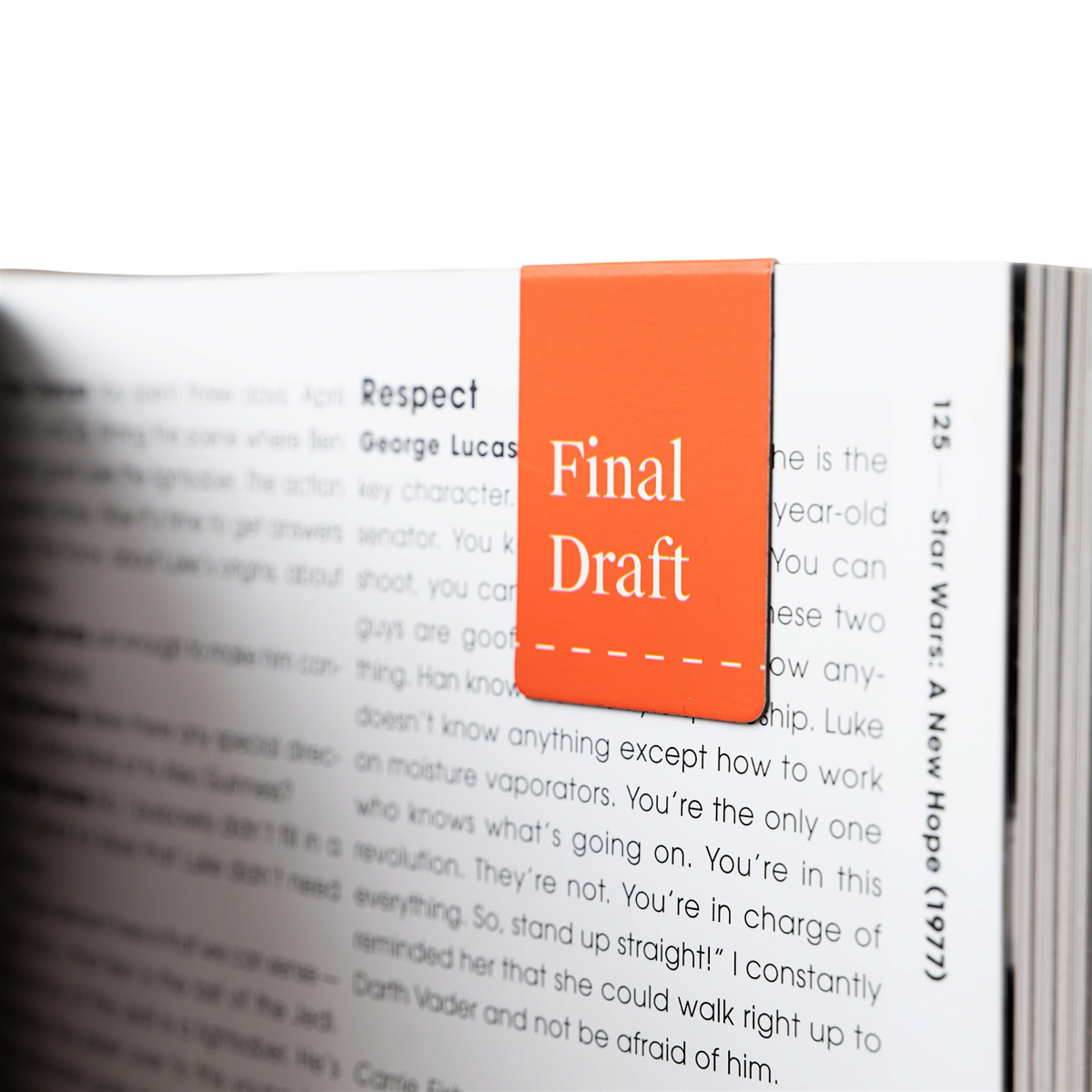 A close-up of an open book with printed text, featuring an orange page marker clipped over a page with the words 'Final Draft' in white text.