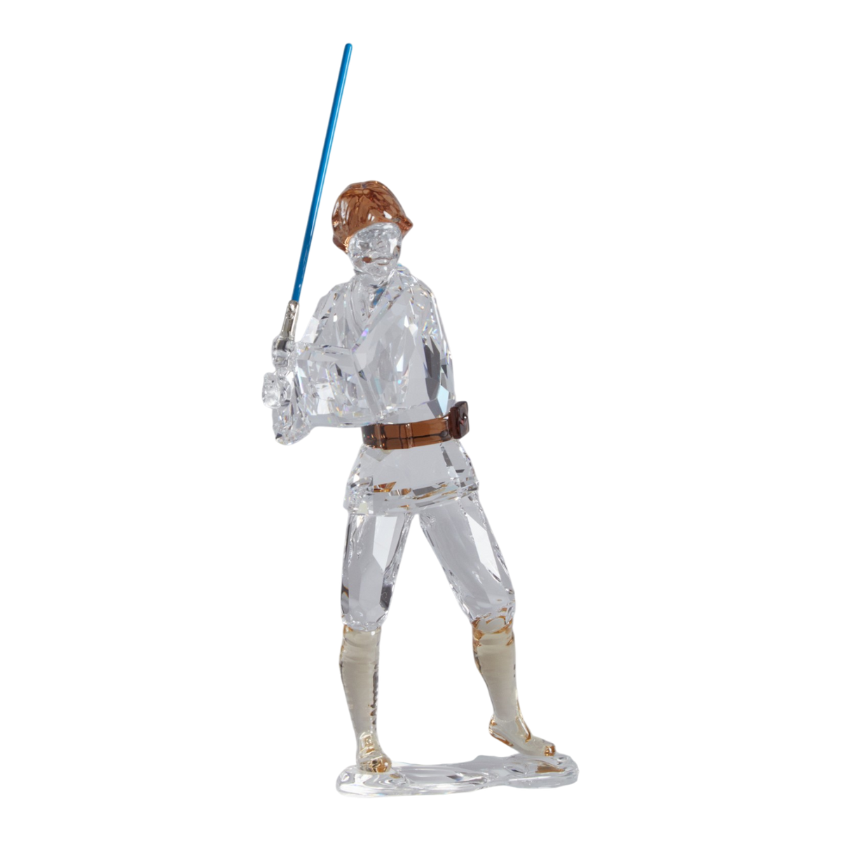 A clear faceted Swarovski crystal figurine of Luke Skywalker holding a blue sword, standing on a transparent base against a plain white background.