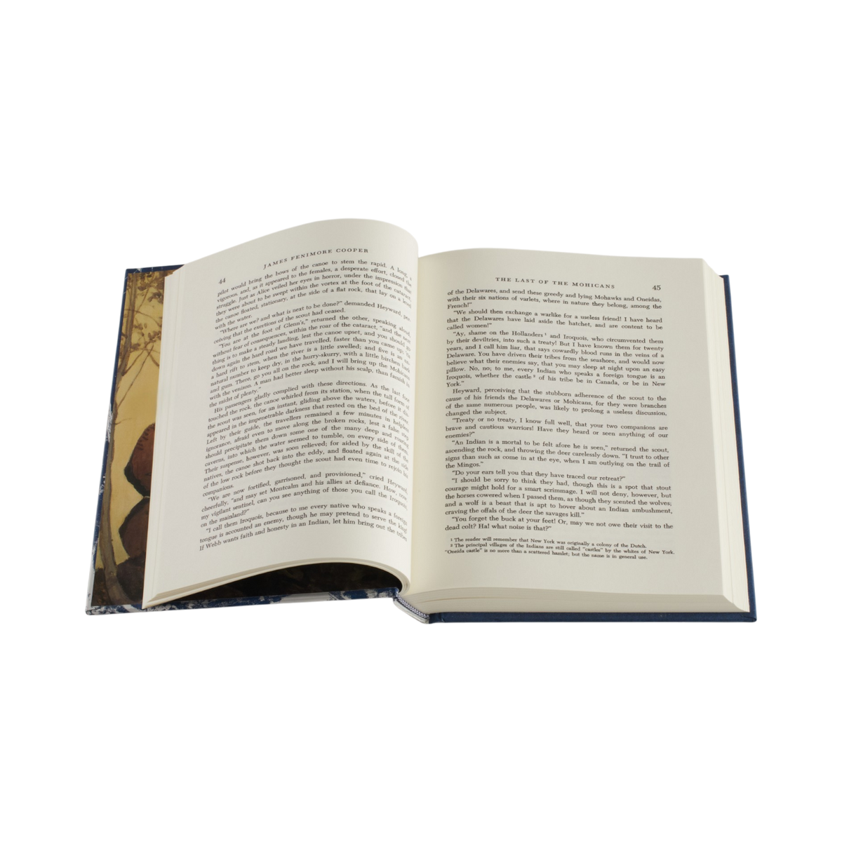 An open hardcover book with printed text on both pages, photographed on a plain white background. The cover shows a dark patterned design with a small illustrated figure.