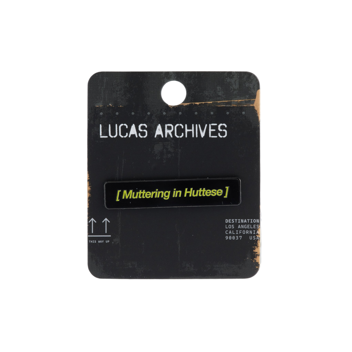 A black rectangular enamel pin with yellow text reading '[Muttering in Huttese]' mounted on a black Lucas Archives display card, photographed against a plain white background.