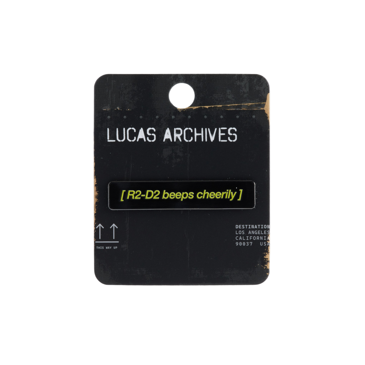 A black rectangular pin with yellow text reading '[R2-D2 beeps cheerily]' mounted on a black card labeled 'LUCAS ARCHIVES', shown on a plain white background.