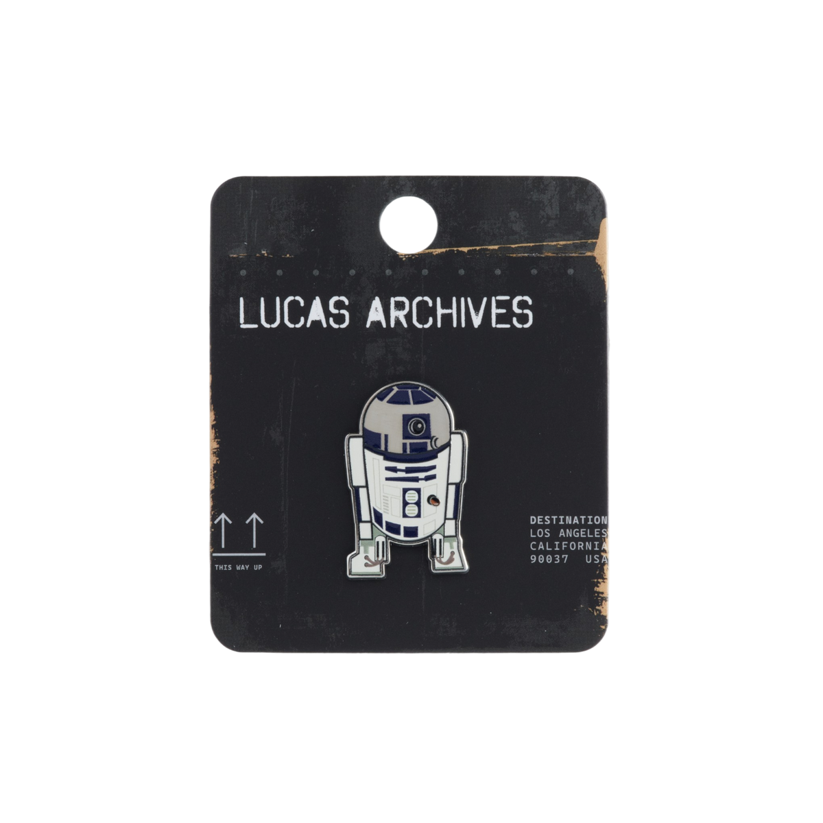 A Lucas Archives enamel pin of the Star Wars droid R2-D2, mounted on a black cardboard display card with distressed edges.