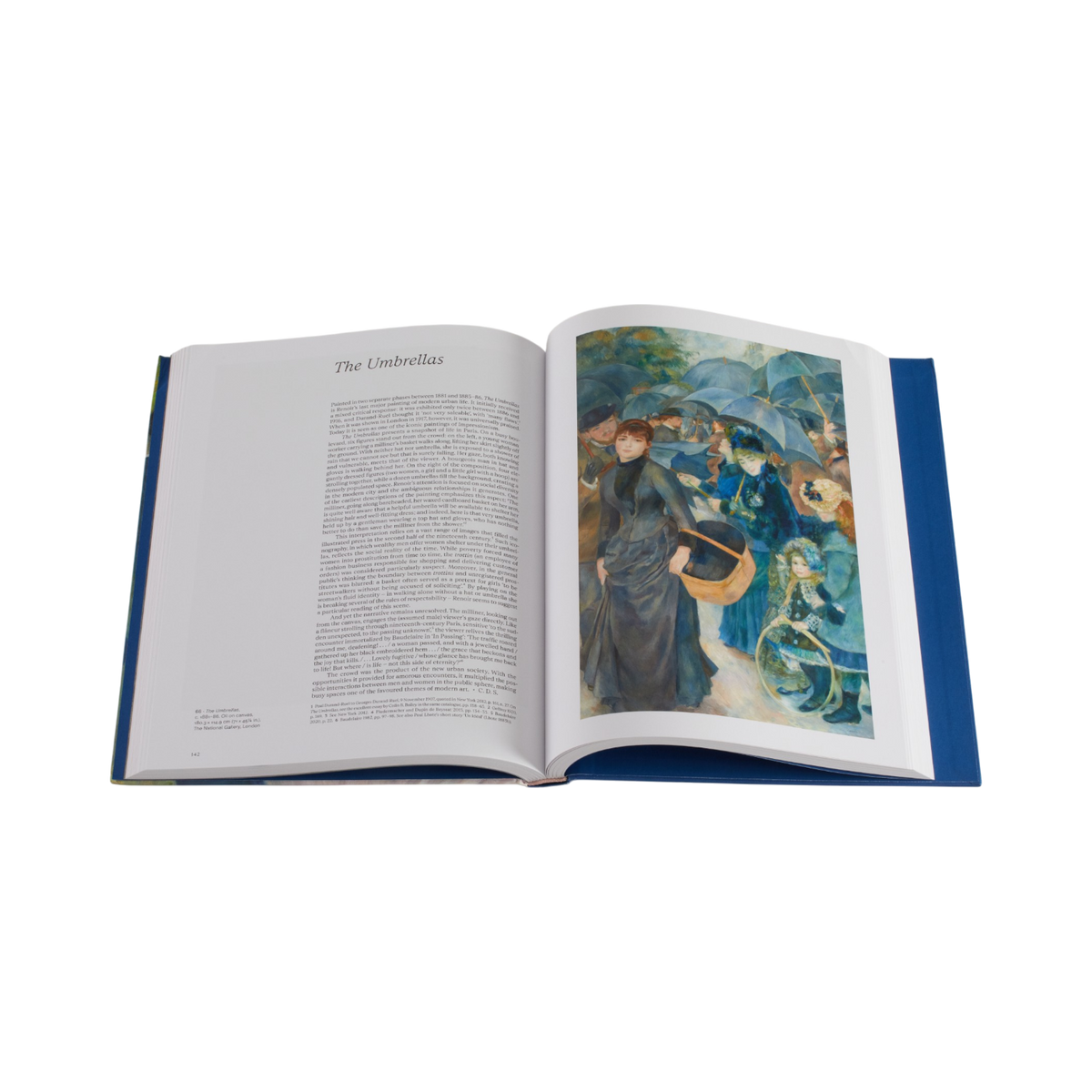 An open hardcover book on a plain white background, showing a printed text page on the left and a colorful artwork on the right. The book has a blue cover and is photographed from above.
