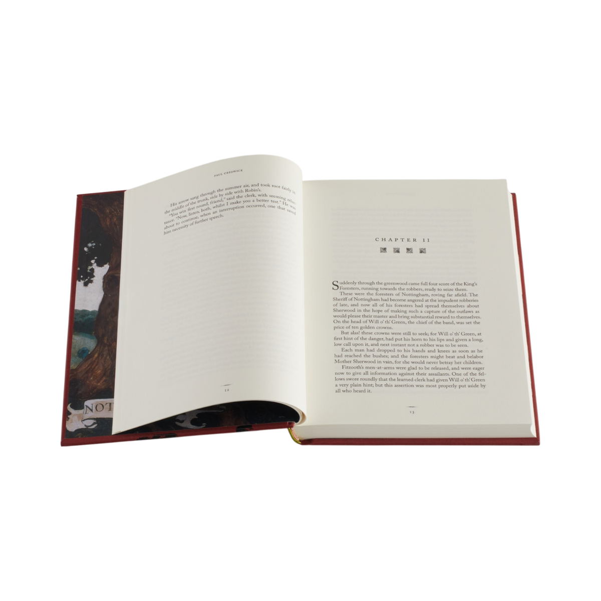 An open hardcover book with cream-colored pages, showing printed text and a dark illustrated cover detail on the left page, isolated on a white background.