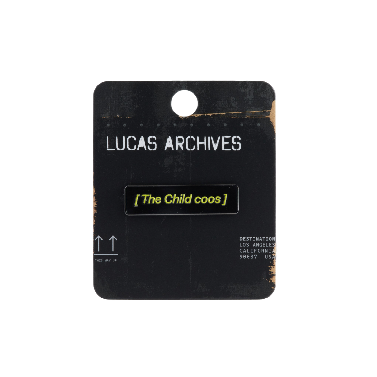 A black enamel pin with yellow text reading '[ The Child coos ]' mounted on a black display card labeled 'LUCAS ARCHIVES'.