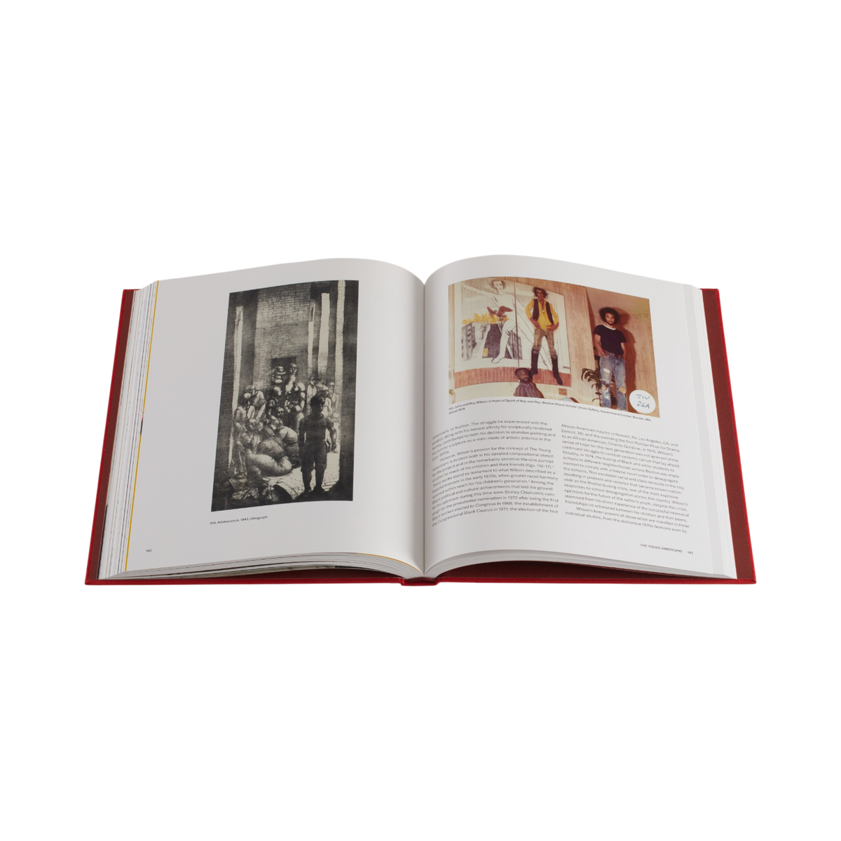 An open hardcover book with red sides, showing two printed pages with black-and-white and color historical photographs and text, photographed on a plain white background.